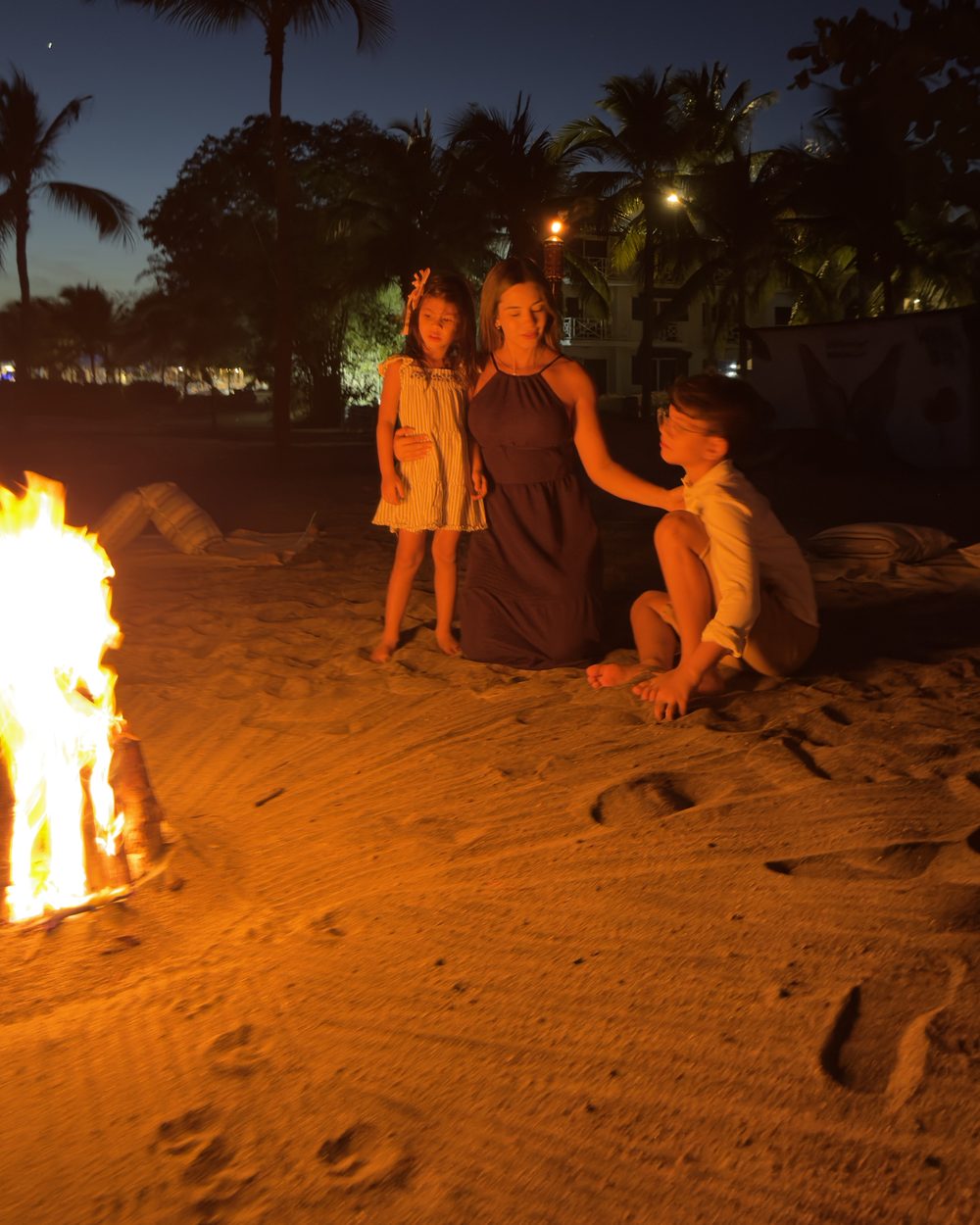 A family by the bonfire on the beach after sunset